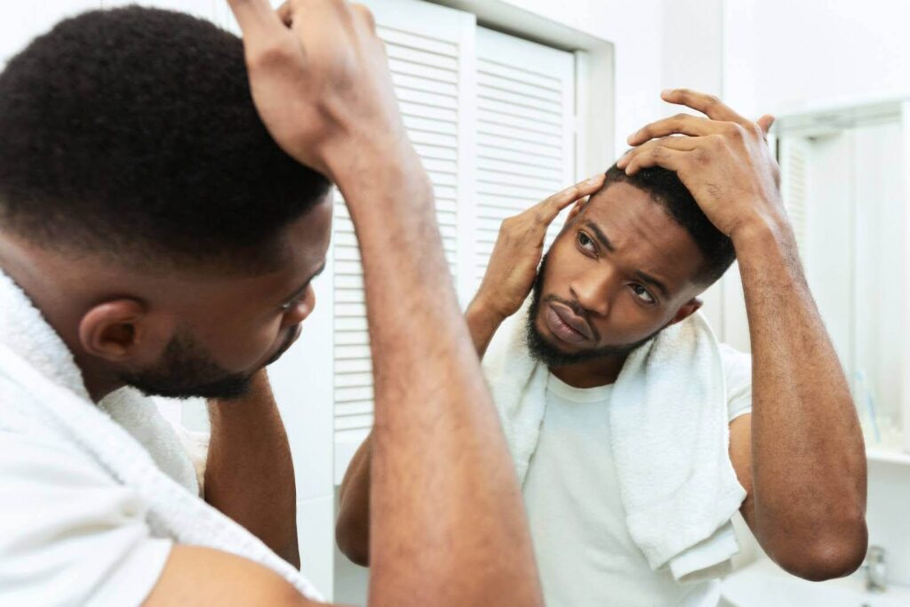 A man examining his hairline in the mirror