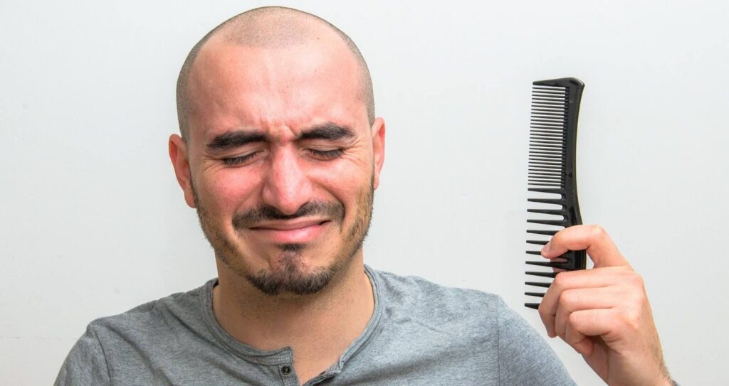 Man in Tennessee looking at hair loss in a mirror.