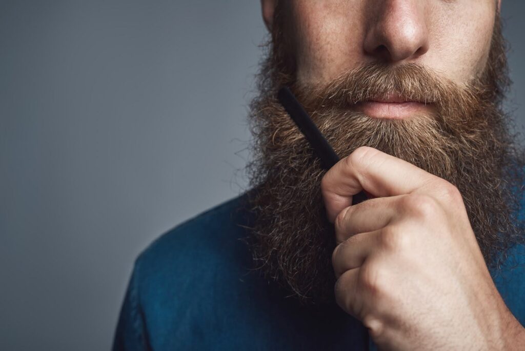 Closeup of a young man styling his long beard